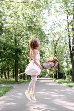 Cute little girl in a park jumping with her hobbyhorse