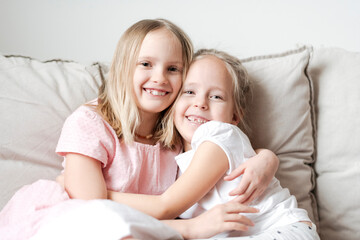 Portrait of two little girls hugging each other on the couch