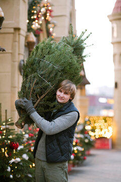 Smiling man with fir tree on his shoulder