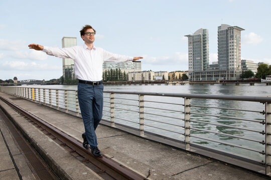 Germany, Berlin, businessman balancing on a rail at River Spree
