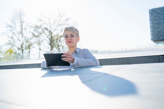 Portrait of young woman leaning on wall using digital tablet