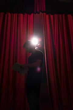 Actor standing on stage of theatre studying script