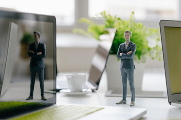 Businessman figurine standing on desk with mobile devices