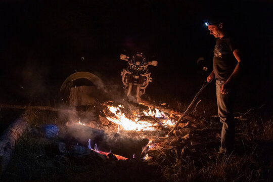Man on a motorbike trip at night at camp fire