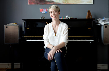 Portrait of laughing woman sitting in her music room in front of piano