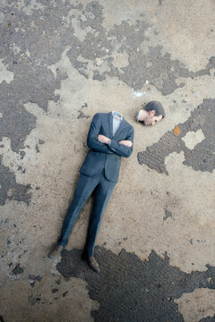 Headless businessman figurine laying on cocrete