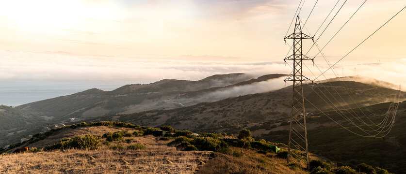 Spain, Electricity pylon against hills of GibraltarÔøΩshrouded in clouds