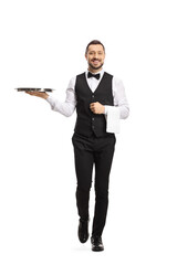 Full length portrait of a waiter carrying a silver tray and walking towards camera