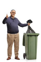 Mature man throwing a plastic bag in a dustbin and gesturing a thumb up sign