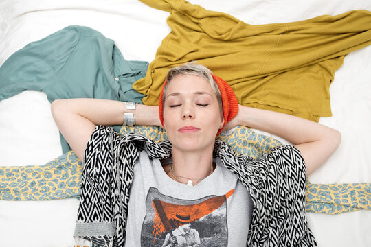 Portrait of stylish woman lying on clothing with eyes closed