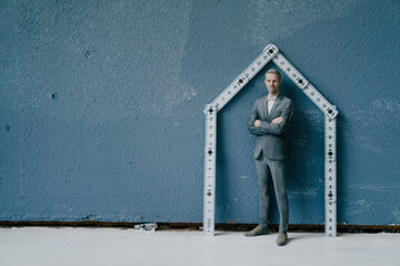 Pastic figurine, businessman and pocket rule as house