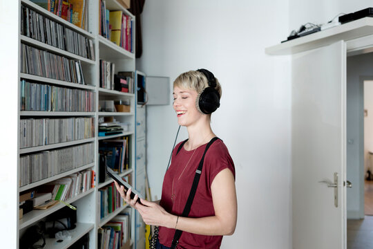 Happy woman listening to music with headphones at home