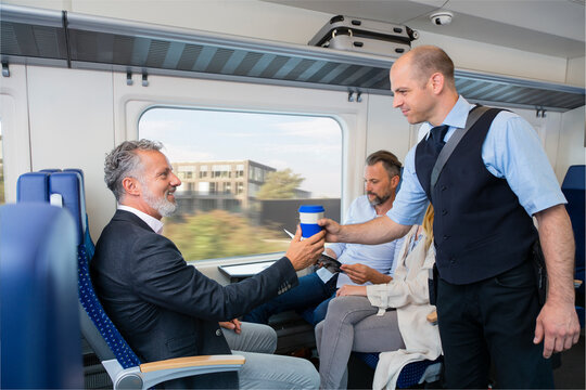 Conductor serving coffee to a train passenger