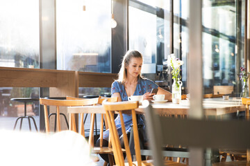 Woman using cell phone in a cafe