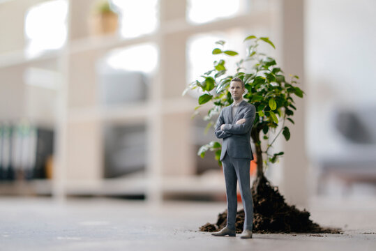Businessman figurine standing next to a little tree