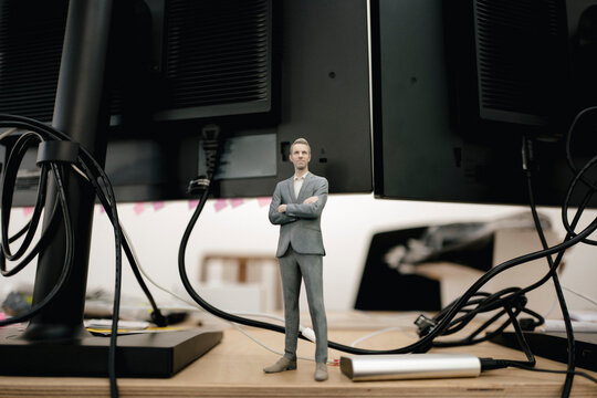Businessman figurine standing under computer screens