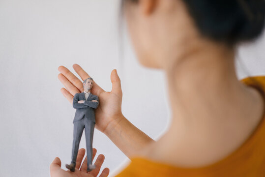 Young woman holding miniature figurine of her boss