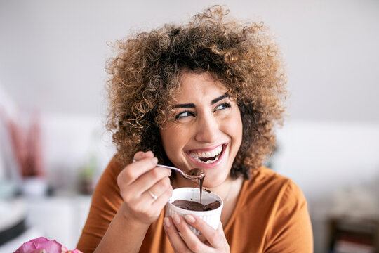 Portrait of happy woman eating chocolate spread at home