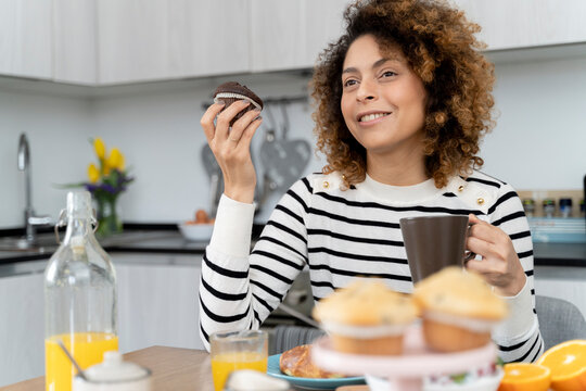 Woman sitting in kitchen, having breakfast