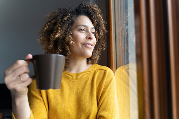 Woman sitting at window, taking a break, drinking coffee