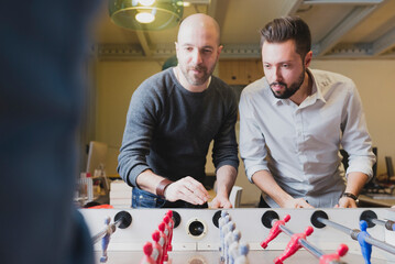 Colleagues playing foosball in office