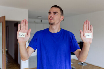 Young man in empty apartment with notes on the palms of his hands