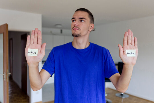 Young man in empty apartment with notes on the palms of his hands