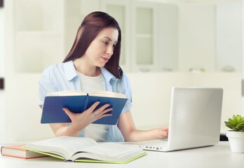 Caucasian female student working from home writing, sitting next to books