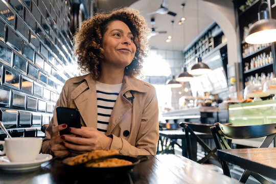 Smiling woman with cell phone in a cafe