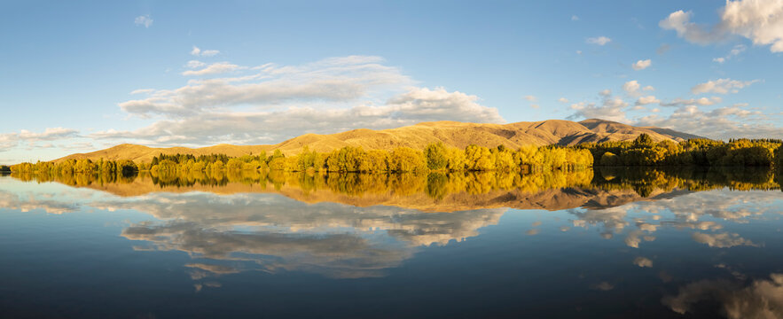 New Zealand, Franklin District, Glenbrook, Forested hills reflecting in Wairepo Arm lake in autumn