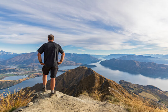 Hiker standing on viewpoint at Roys Peak, looking to Mount Aspiring, Lake Wanaka, South Island, New Zealand