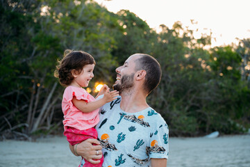 Australia, Queensland, Mackay, Cape Hillsborough National Park, happy father holding his daughter at the beach at sunset