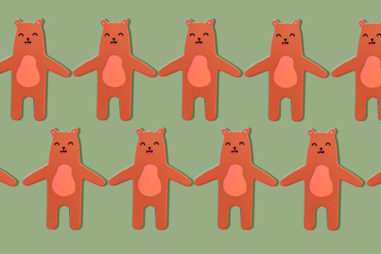 Brown bears, wooden toy in a row holding hands on a khaki green background