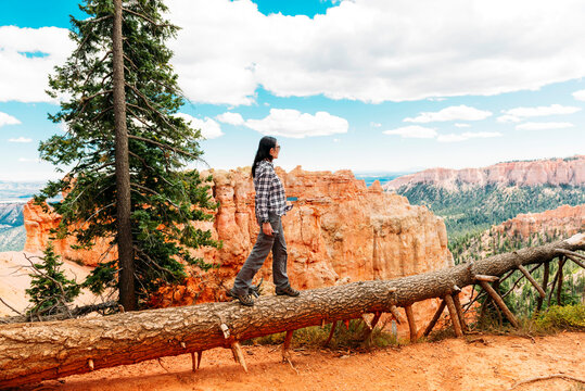 Traveler woman walking on the trunk of a fallen tree enjoying the view in Bryce Canyon, Utah, USA