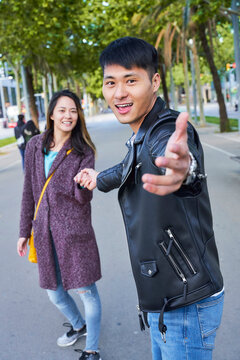 Happy couple inviting someone to join them for a walk, Barcelona, Spain