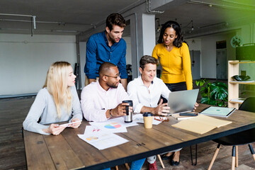Confident business team having a meeting in loft office looking at laptop together
