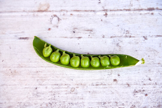 Row of peas in pod on wood