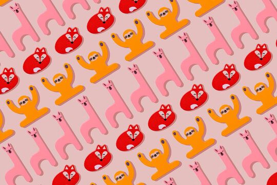 Llama, fox and sloth, wooden toys in a row on pastel pink background