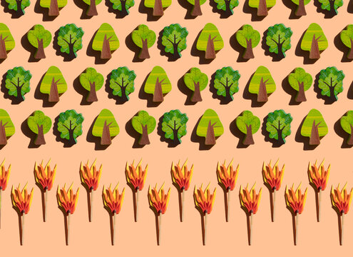 Studio shot of burning matches threatening rows of small wooden trees