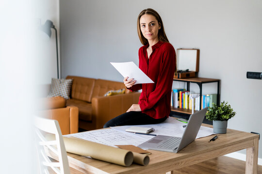 Woman in office holding paper with wind turbine model on table