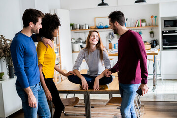 Four happy friends at dining table at home