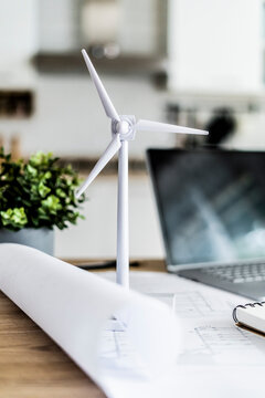 Wind turbine model, construction plan and laptop on table in office