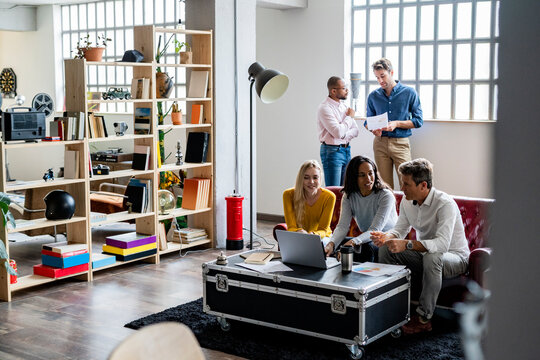 Business team using laptop and discussing documents in loft office