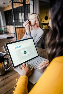 Businesswomn sitting at conference table in loft office using laptop