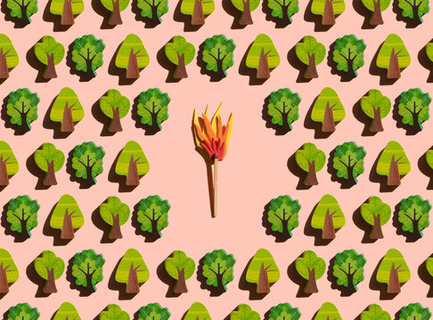 Studio shot of burning match threatening rows of small wooden trees