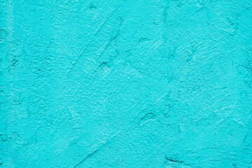 Rough plaster wall, bright turquoise color, scratched surface, background