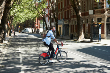 Young man using rental bike in the city, London, UK