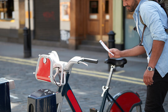 Crop view of man using rental bike in the city, London, UK
