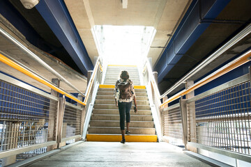 Businesswoman with backpack walking on steps in subway station