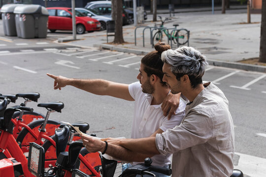 Man pointing while sitting on rented bicycle by partner in city